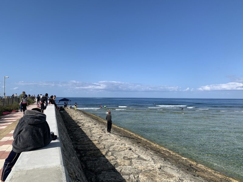 People sitting on top of Sunabe Seawall, looking out over the reef