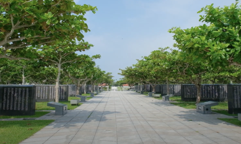 A tree-lined path between rows of black stone walls at Peace Memorial Park