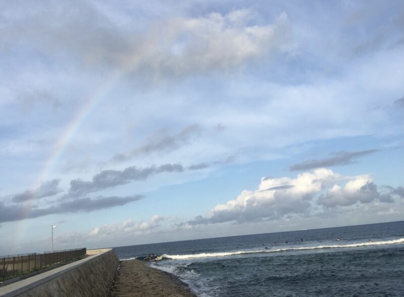 A rainbow over the seawall and small waves at Sunabe