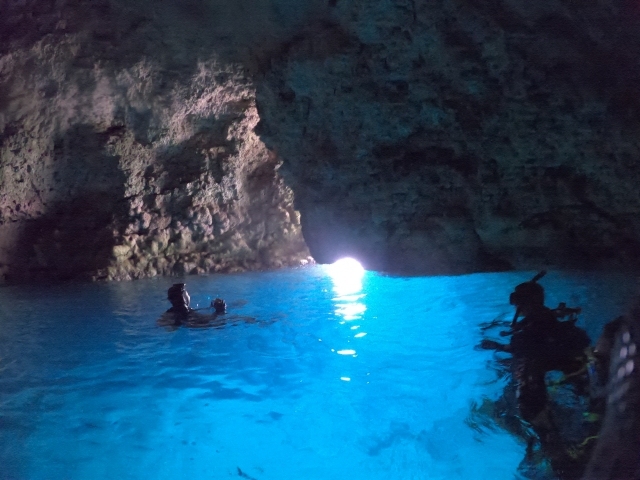 Snorkelers in the glowing blue water inside the Blue Cave