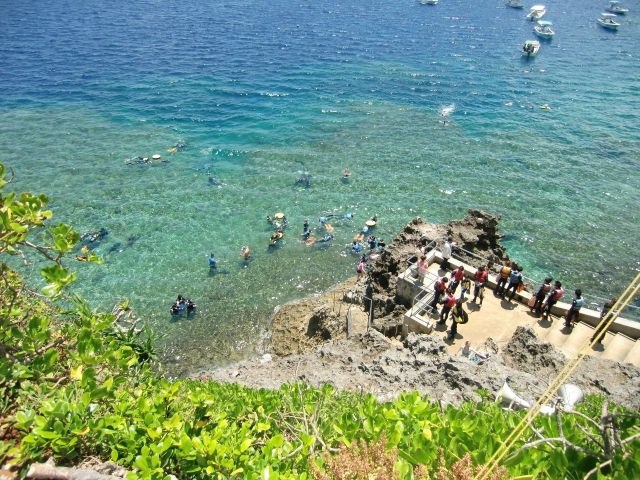 Snorkelers in the water around the entry point at the bottom of the stairs
