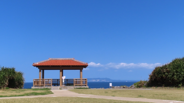 A red-roofed gazebo on the lawn at Cape Maeda, with the sea behind it